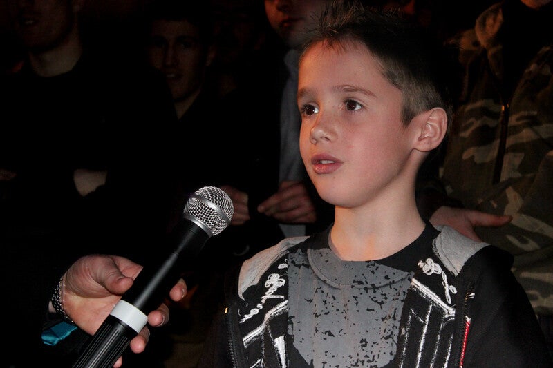 A young boy bravely speaking into a microphone at the Randy Couture event in Manchester