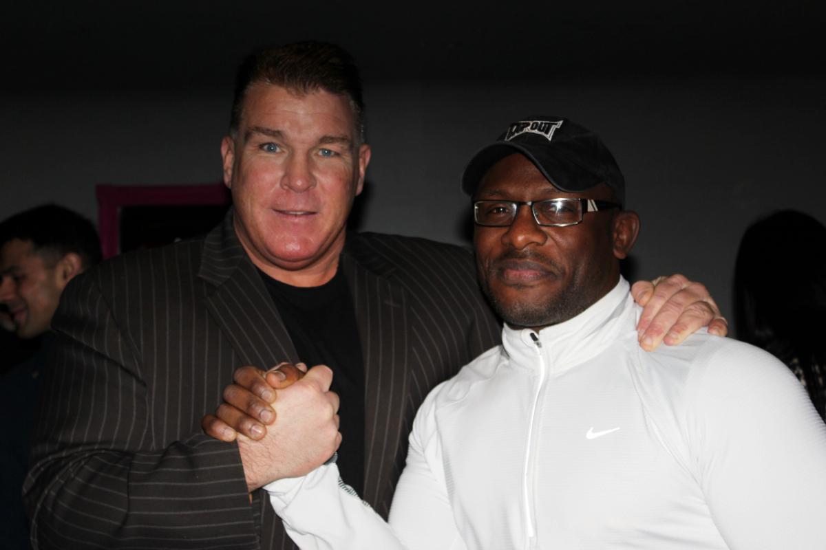 Big Joe Egan clasping hands with Andy Farrel, both smiling, Fiaz Rafiq visible in the background