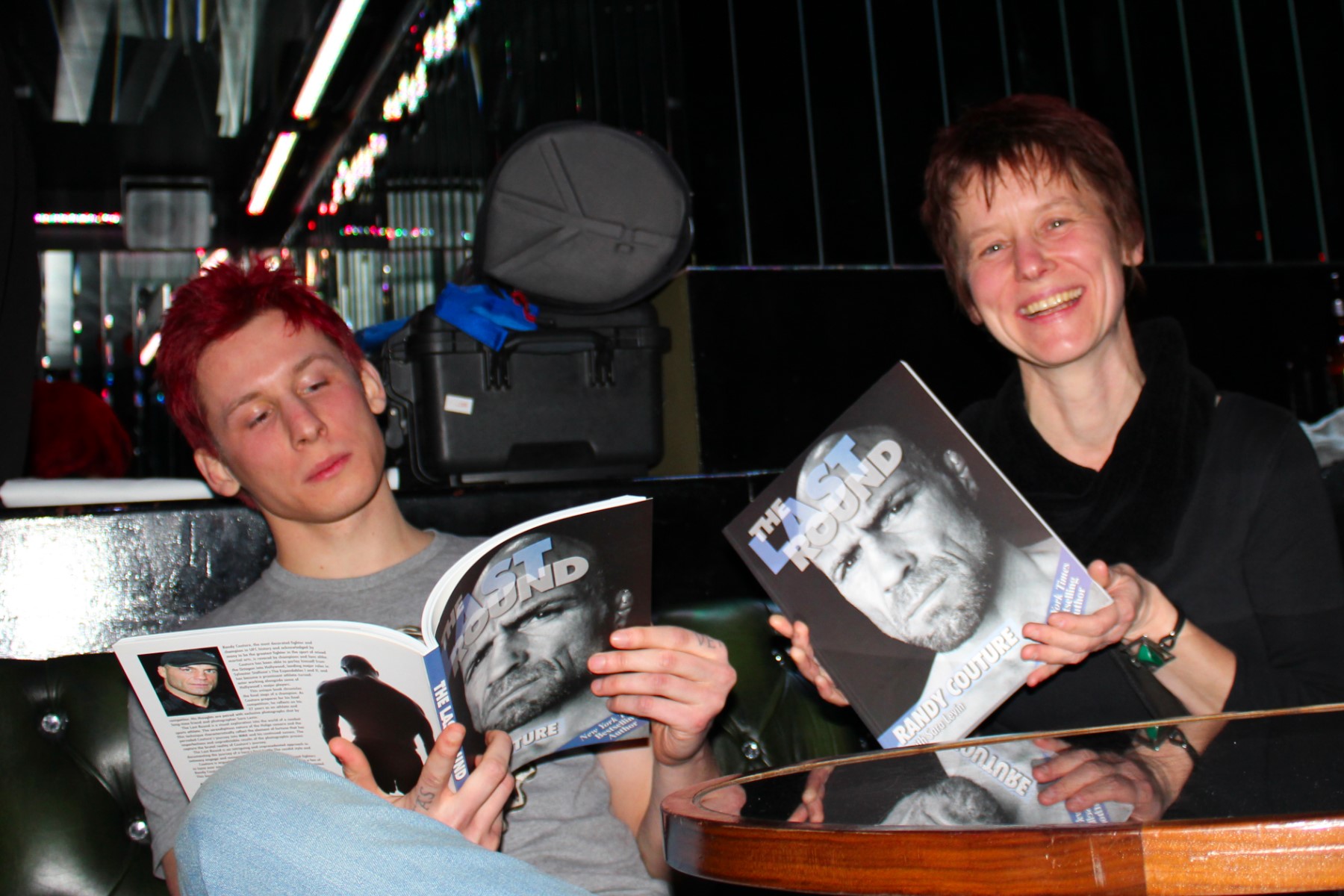 A mother and her son sitting at a coffee table in London, both holding copies of The Last Round