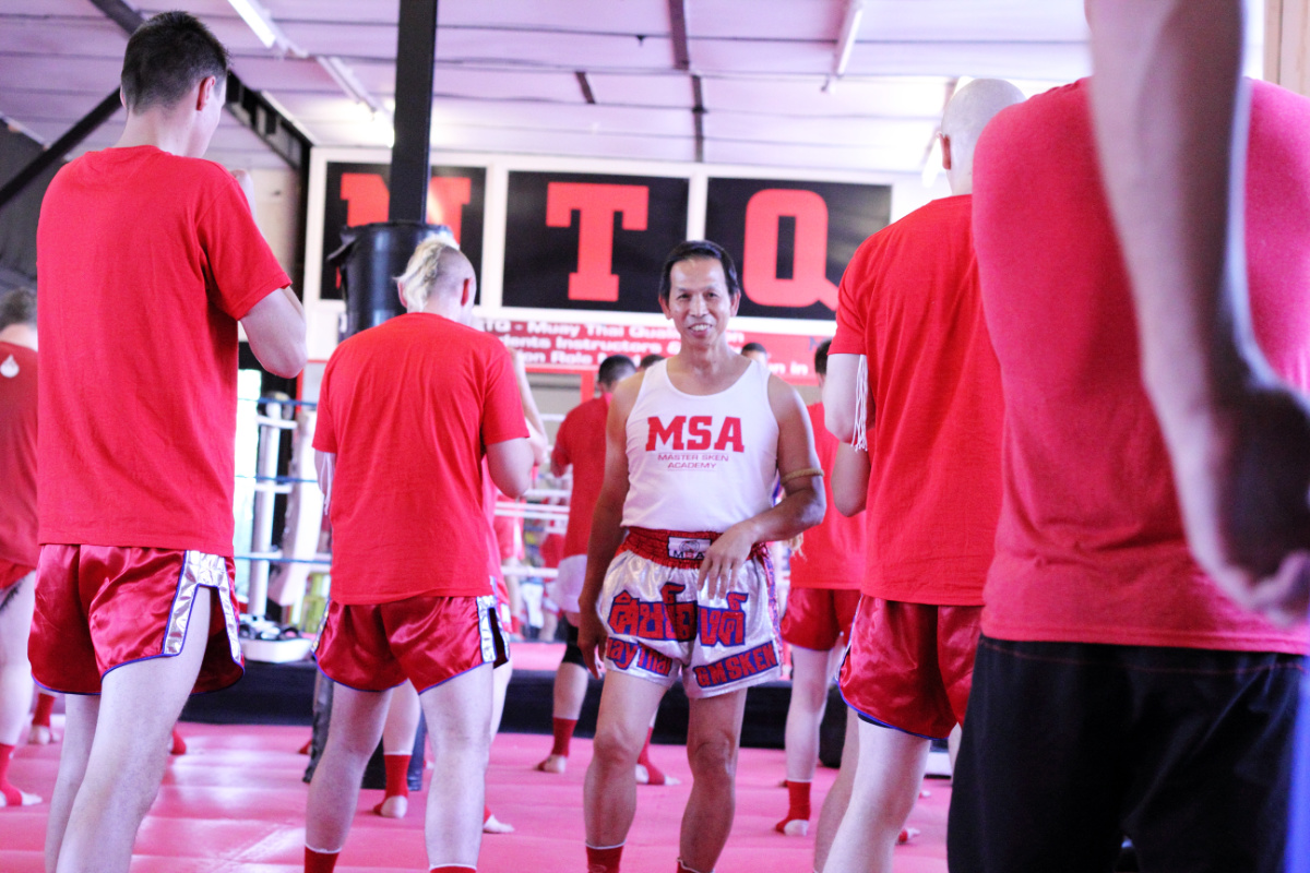 Grandmaster Sken smiling in the centre of his gym surrounded by students in red MSA t-shirts during the Polish master grading class in Manchester